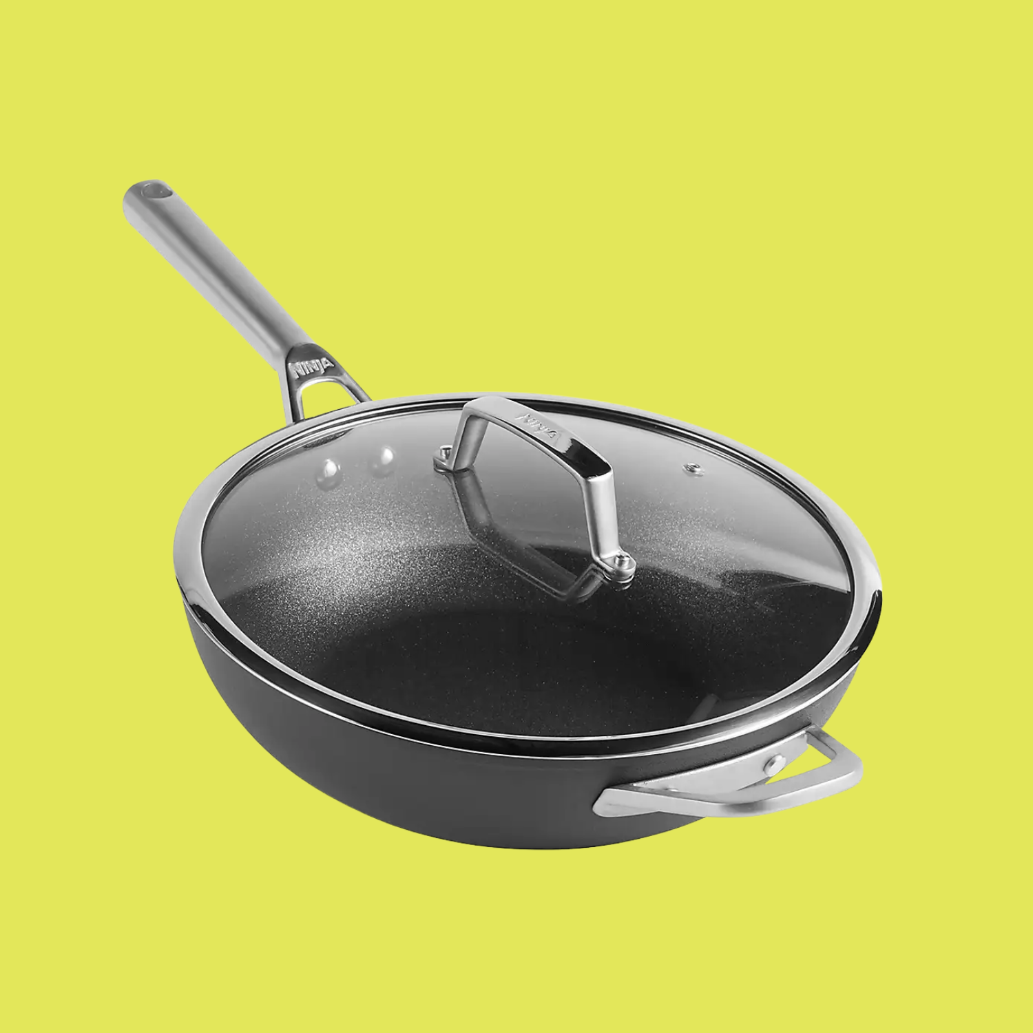 A black zero stick wok with a lid from Ninja, against a lime yellow background