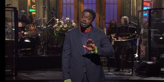 Daniel Kaluuya in a blue suit with green accents on the Saturday Night Live stage about to make a joke.