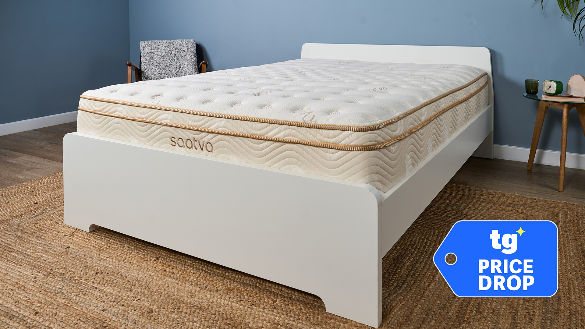 The Saatva Classic mattress on a white bed frame in a bedroom, a Tom's Guide price drop deals badge in the bottom right corner