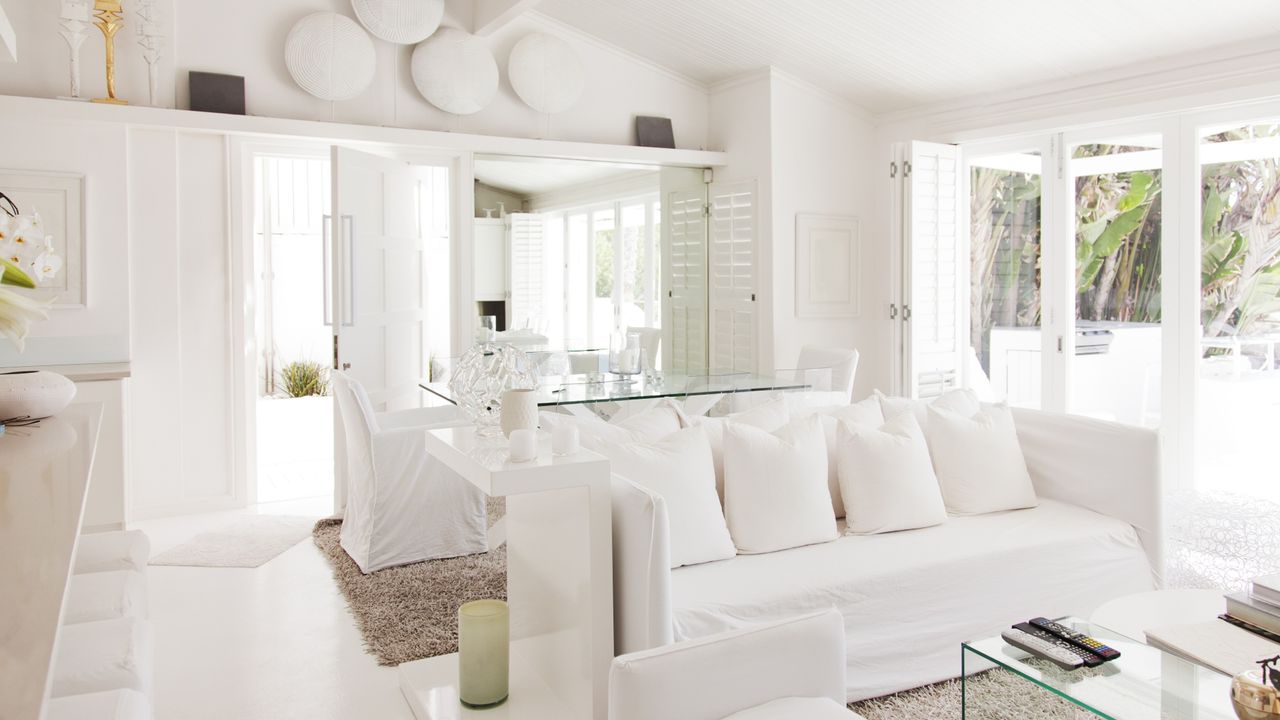 All white living room with sofa, cushions, table