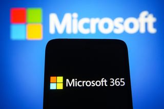 Microsoft 365 logo is seen on a smartphone screen with a Microsoft logo in the background