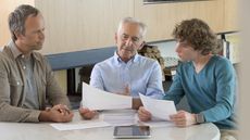 A father, grandfather and grandson look at financial paperwork together.