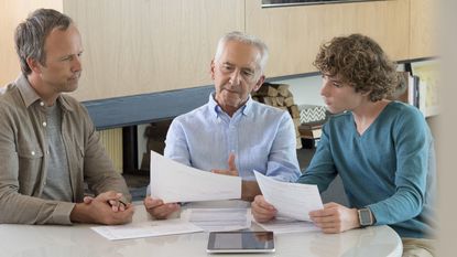A father, grandfather and grandson look at financial paperwork together.