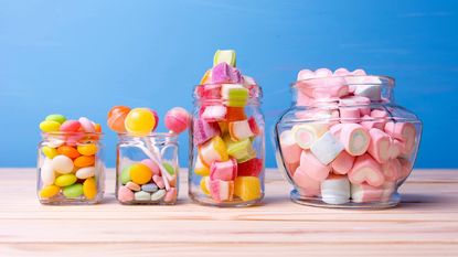 Colorful candy in glass jars against blue background