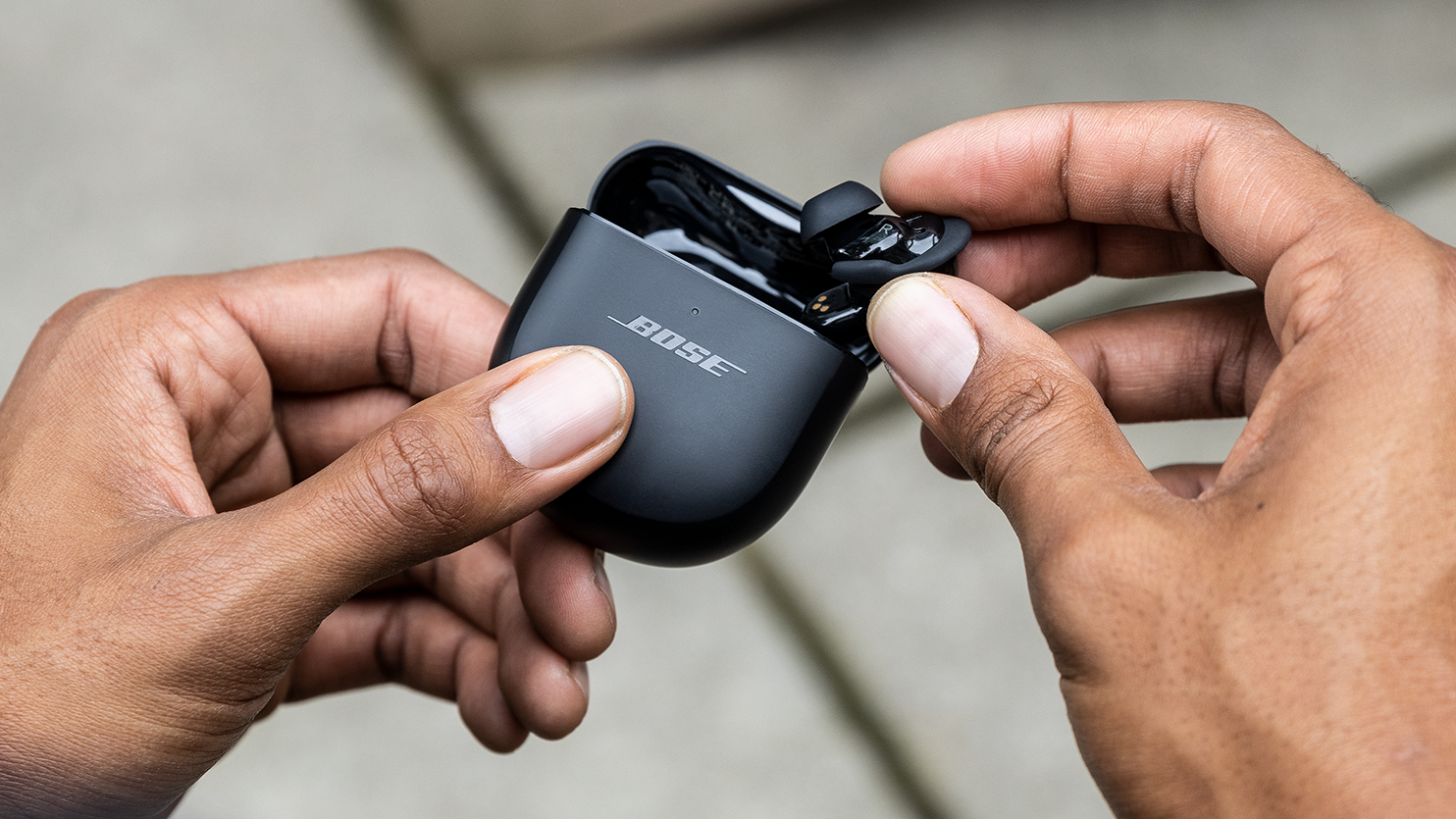 Bose QuietComfort Earbuds II being taken out of their case by two hands