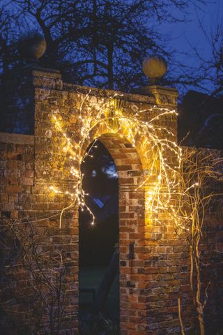 christmas lights around an outdoor arched gateway