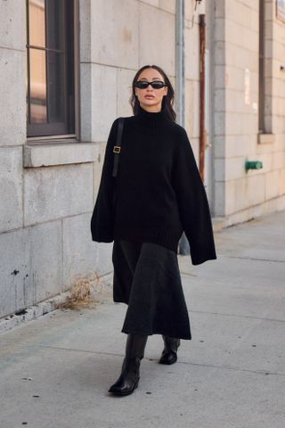 woman wearing a black turtleneck sweater, black skirt, and black boots