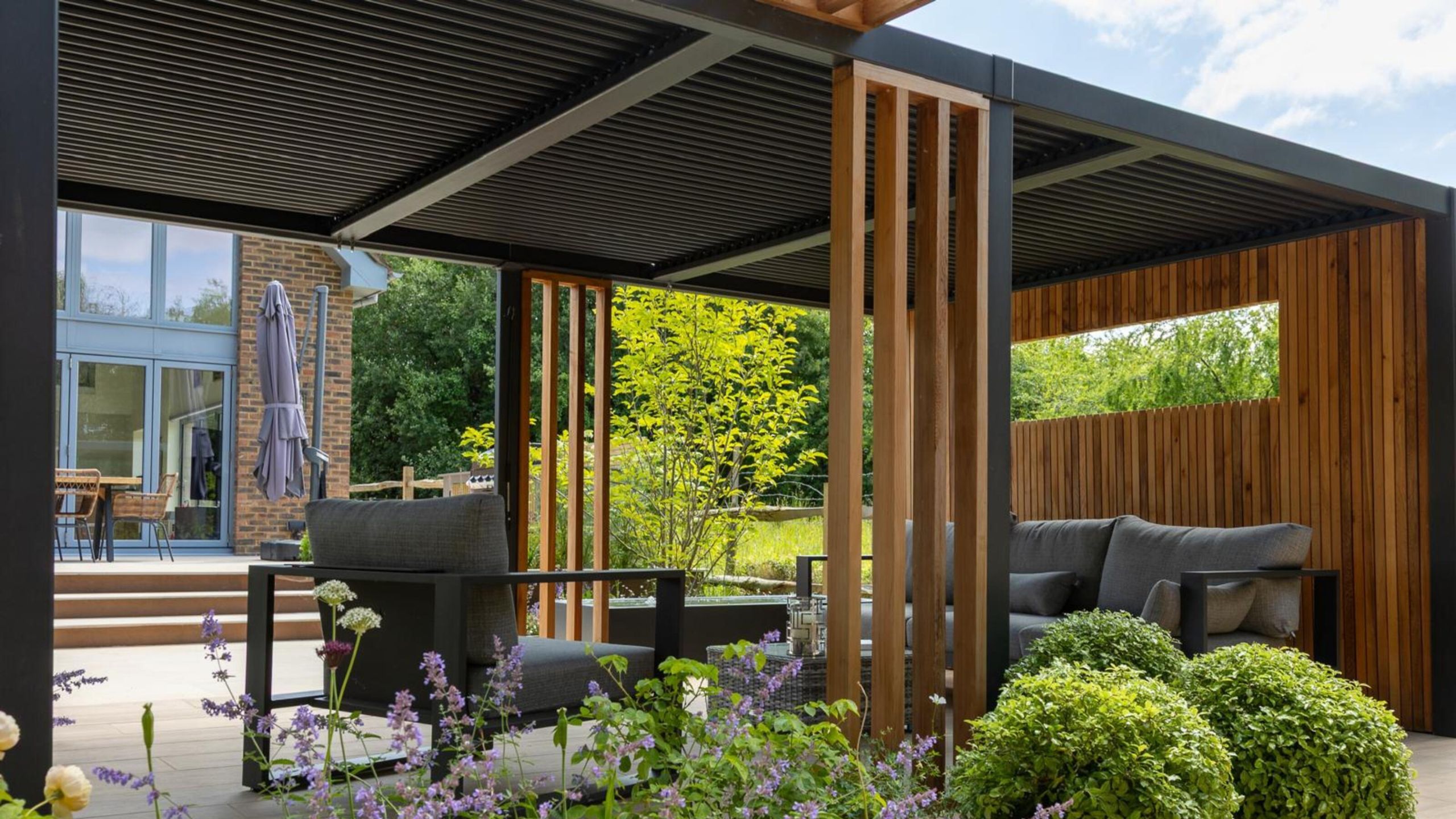 A modern patio with a large contemporary pergola offering shade for an outdoor seating area