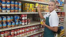 Teenage supermarket employee stocking cans