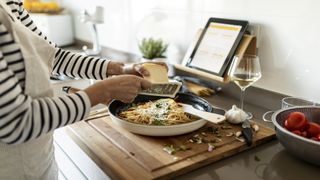 Woman grating cheese over pasta