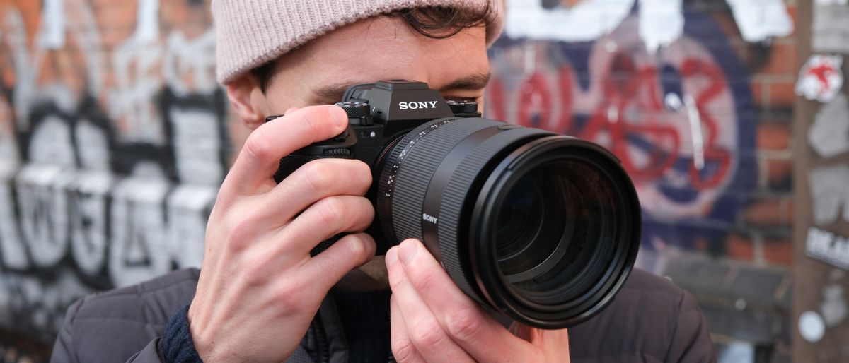 Sony A1 II camera with a Sony FE 28-70mm f/2 GM lens attached held up to a person&#039;s face