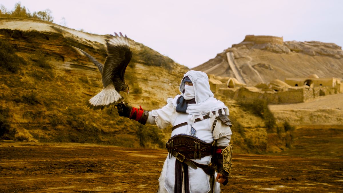 A man with a bird holding a copy of Assassin's Creed.