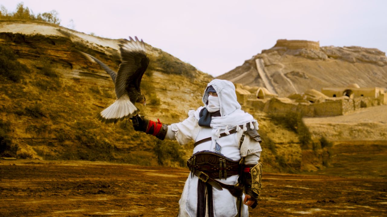 A man with a bird holding a copy of Assassin's Creed.