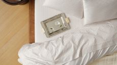 Brooklinen striped luxe sateen bedding and silver martini tray pictured from a bird's eye view inside of a neutral bedroom with hardwood floors