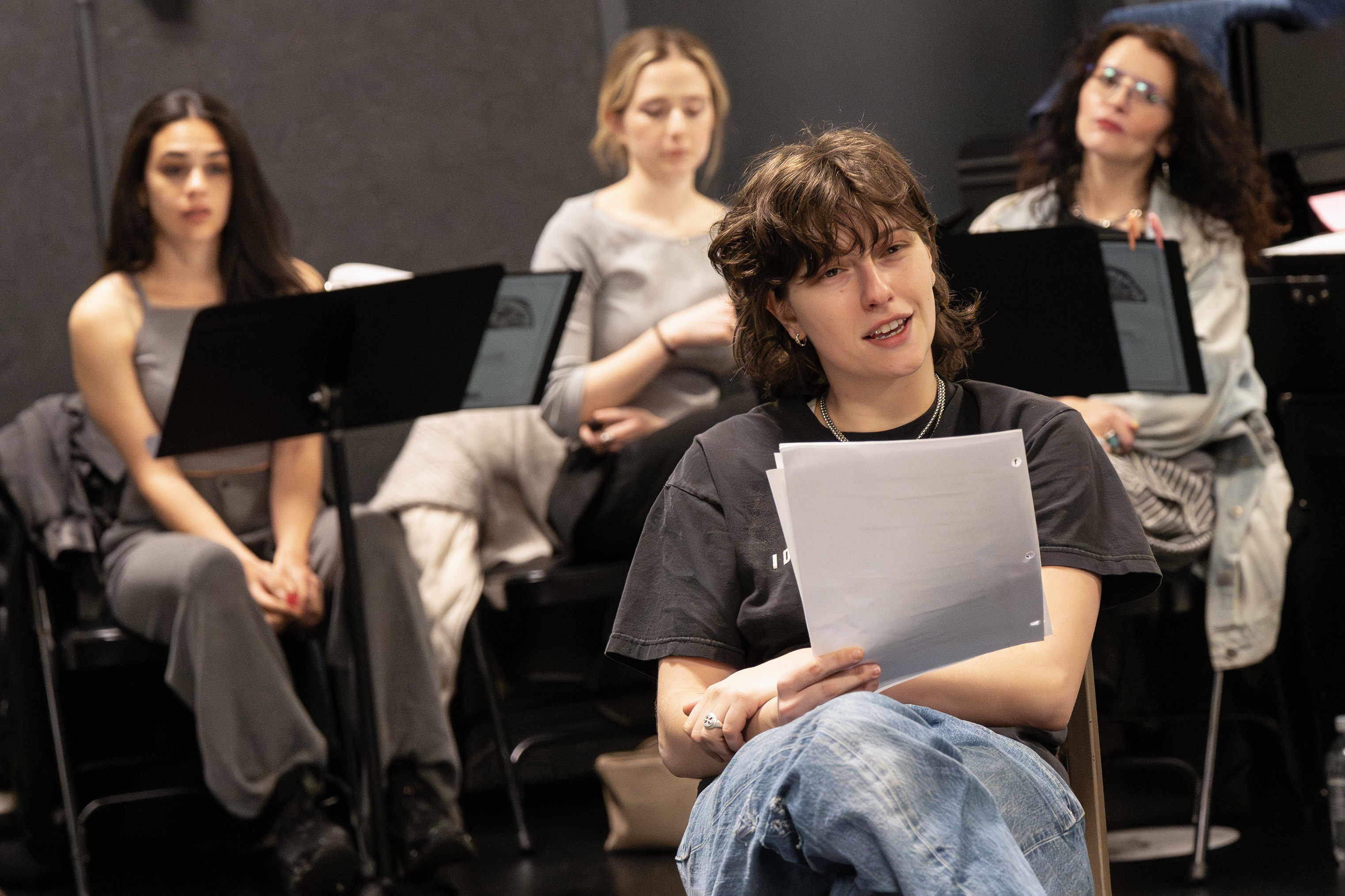 king princess back stage during a rehearsal for girl interrupted the musical reading from the script with her cast mates sitting behind her