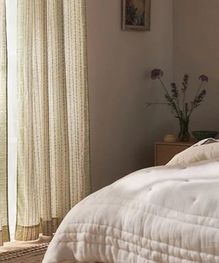 Ellen Merchant Cottage Curtains over a window by a bed with a white comforter.