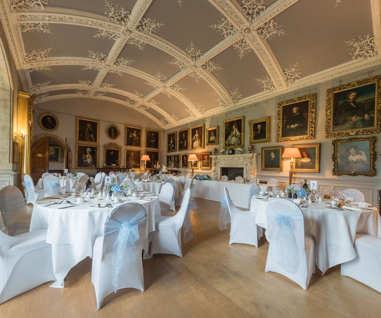 A dining room with white tables and chairs with lots of portraits on the walls