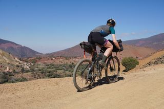 Image shows Anna riding up the Tizi n'Telouet gravel pass in Morocco