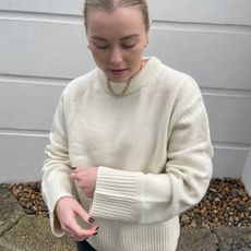 Woman wears cream jumper and black jeans