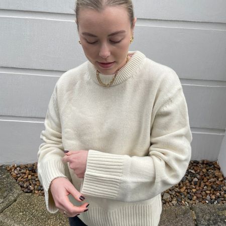 Woman wears cream jumper and black jeans