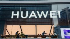 Huawei logo pictured on a store front in Shenzhen, China, with people sitting inside using devices.