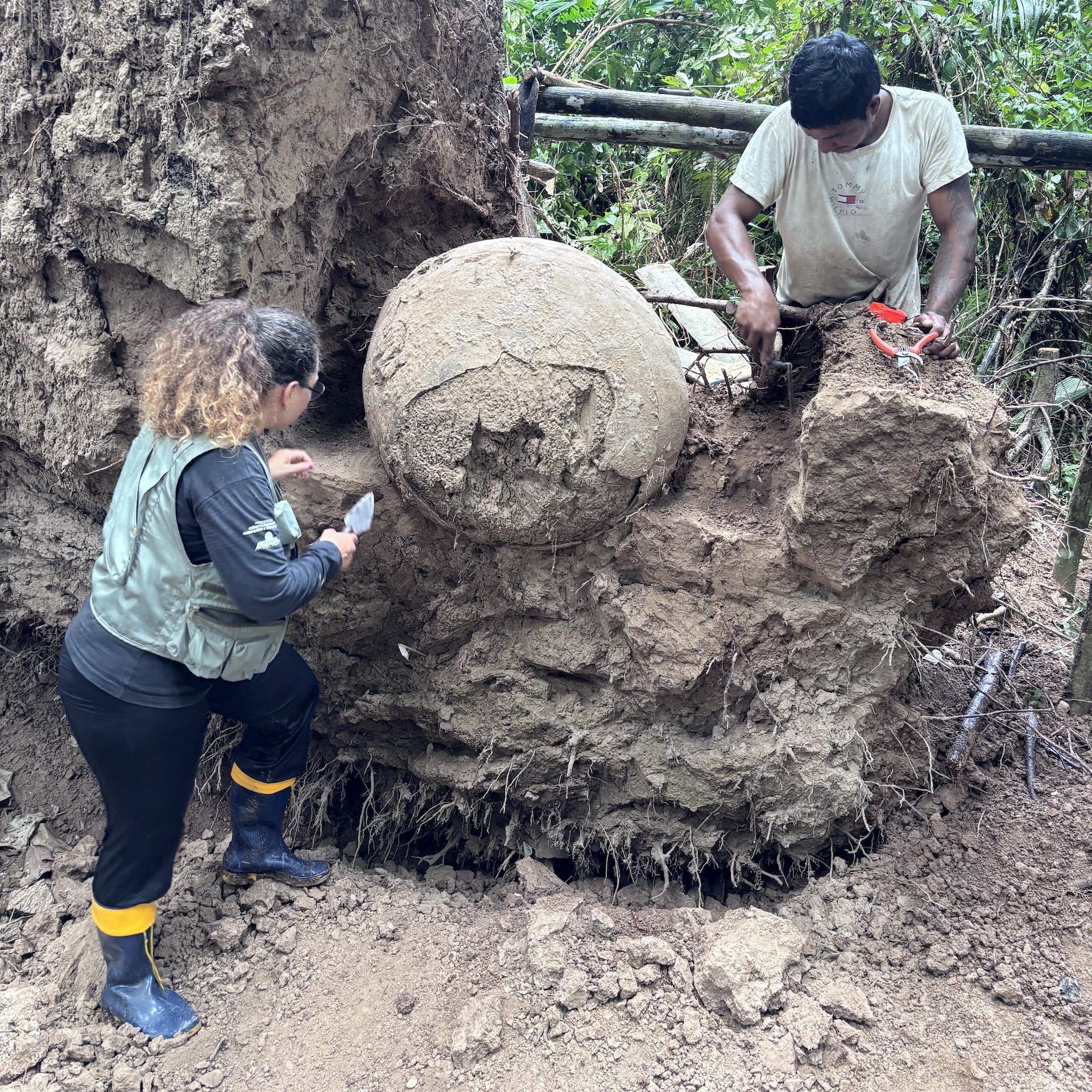 two people excavate a large funeral urn in the rainforest