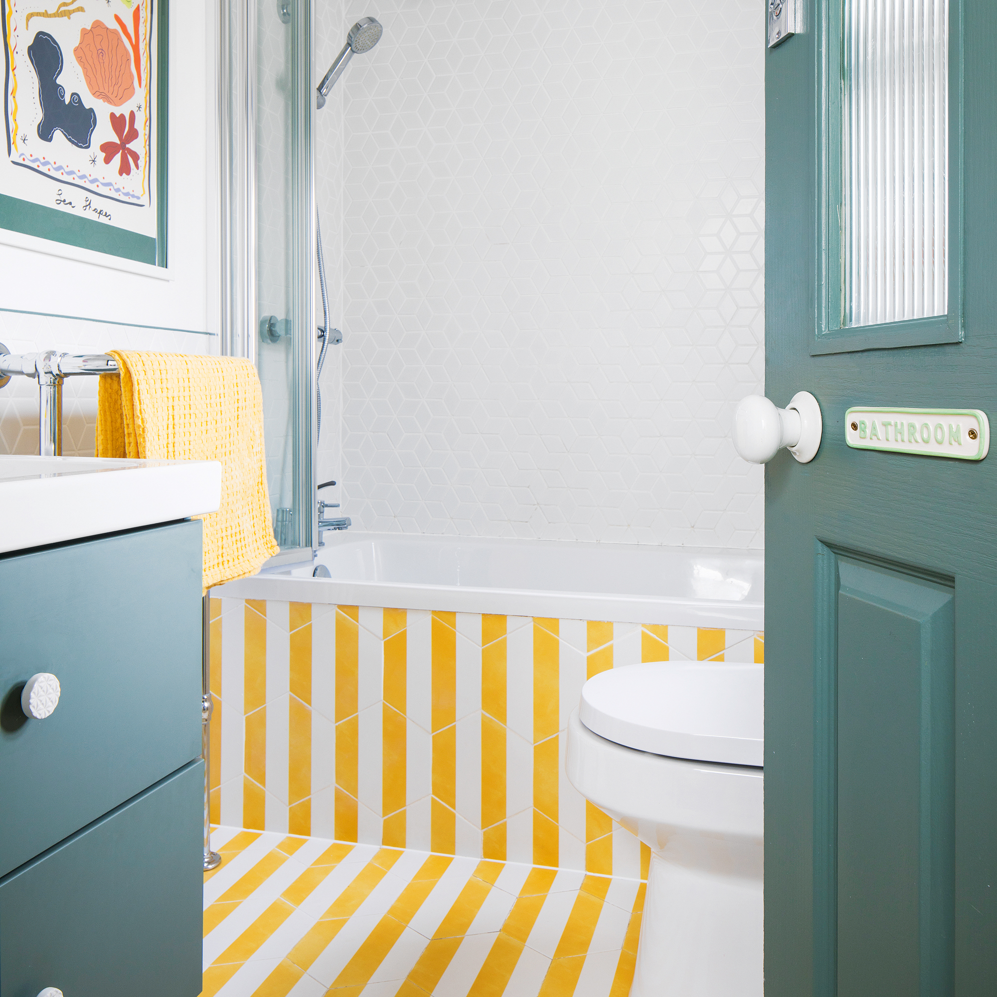 a family bathroom with yellow and white striped floor tiles and green painted woodwork