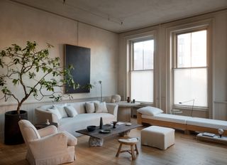 Living room of Colin King's apartment with neutral walls, white sofa, stone coffee table and indoor tree in a pot