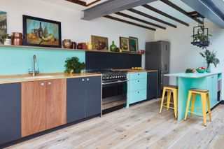 handleless kitchen with cabinets in wood, turquoise and black with yellow bar stools and wooden flooring