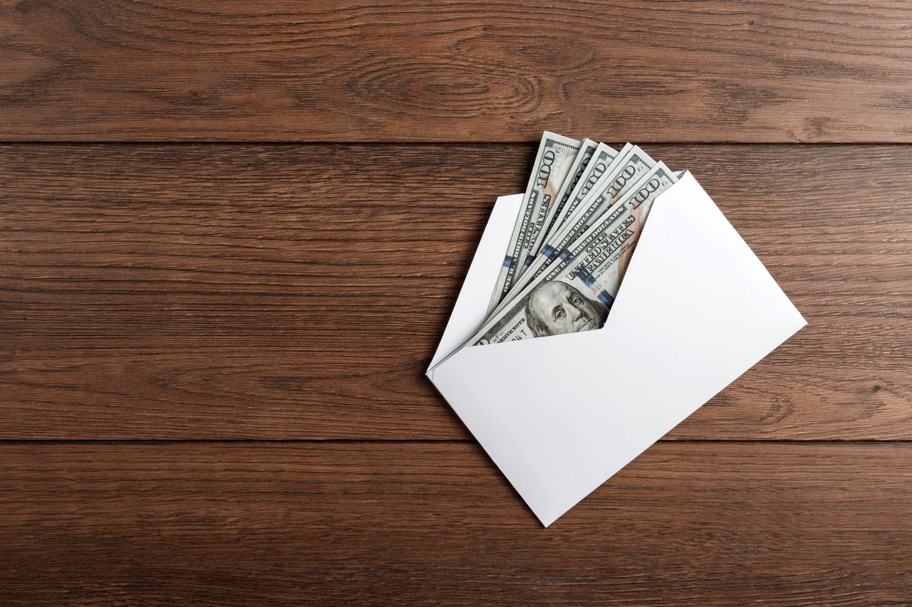 A photo of an envelope containing money on a wooden table