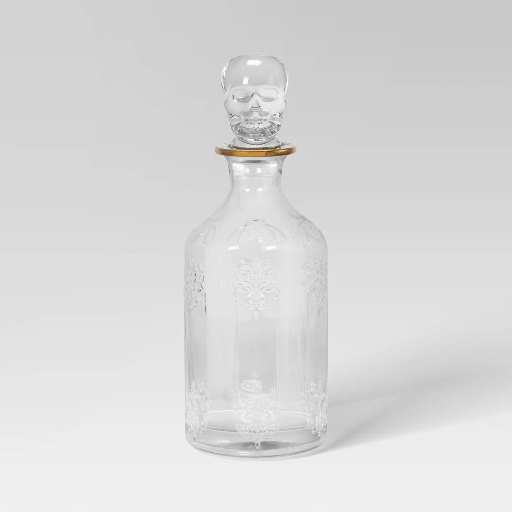 Glass carafe with etched detailing, gold rim, and skull lid
