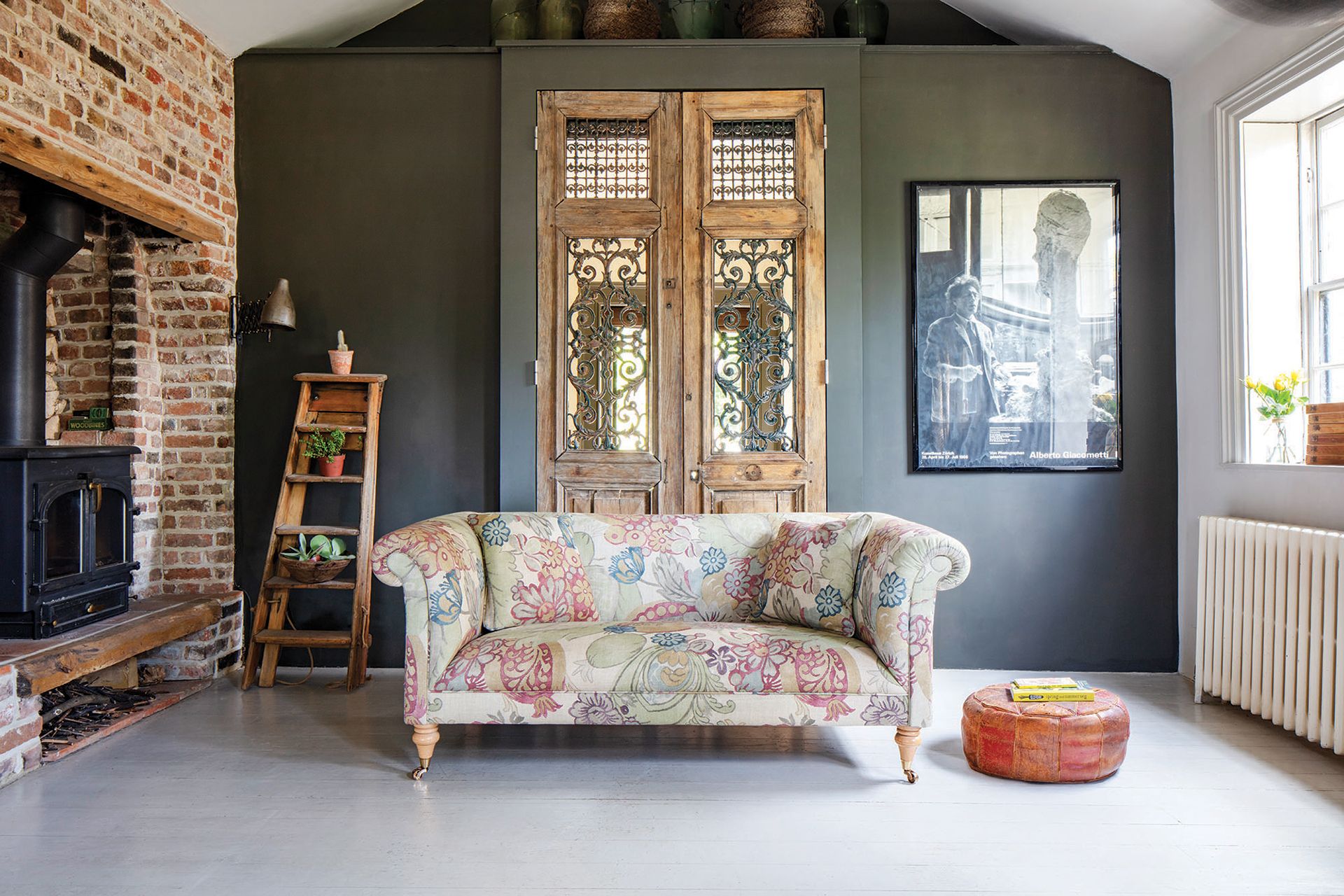 patterned sofa in traditional living room with green walls and brick fireplace