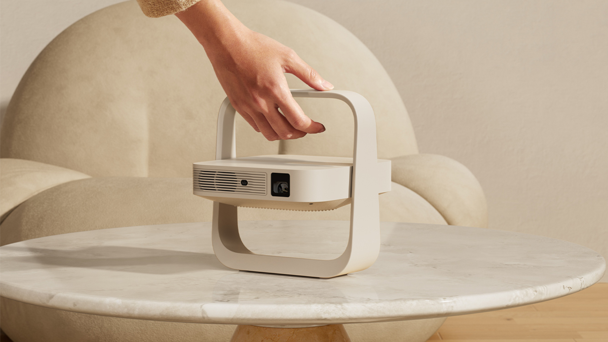 Lifestyle shot of the Xgimi Z6X 5th Generation projector unfolded on a light marble table. A woman's hand is coming from the top of the image to lift the projector up