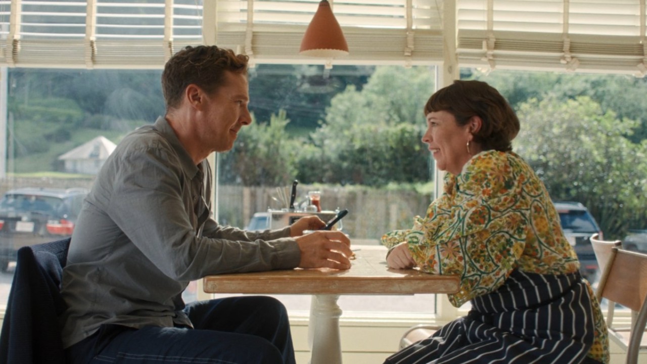 Olivia Colman and Benedict Cumberbatch smiling at each other across the table in The Roses.