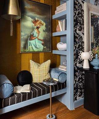 A seating nook in a room with light blue paint and black and white wallpaper