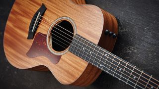 Close up of a Taylor GS Mini acoustic guitar lying on a wooden floor