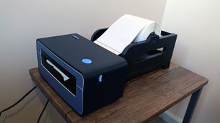 A grey Polono PL60 thermal printer sitting on a wooden table