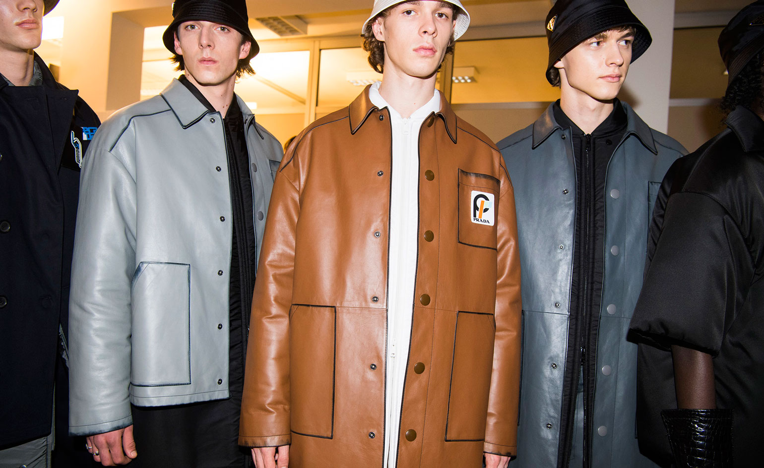 A group of young men wearing button up jackets and hats.