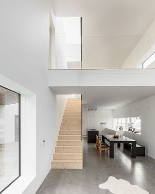 House K interior with grey concrete floors and wooden stairs