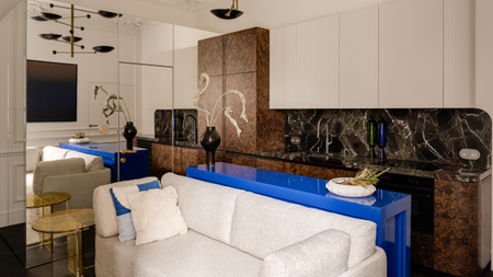 a modern apartment kitchen with burl cabinets, black marble counters and white walls