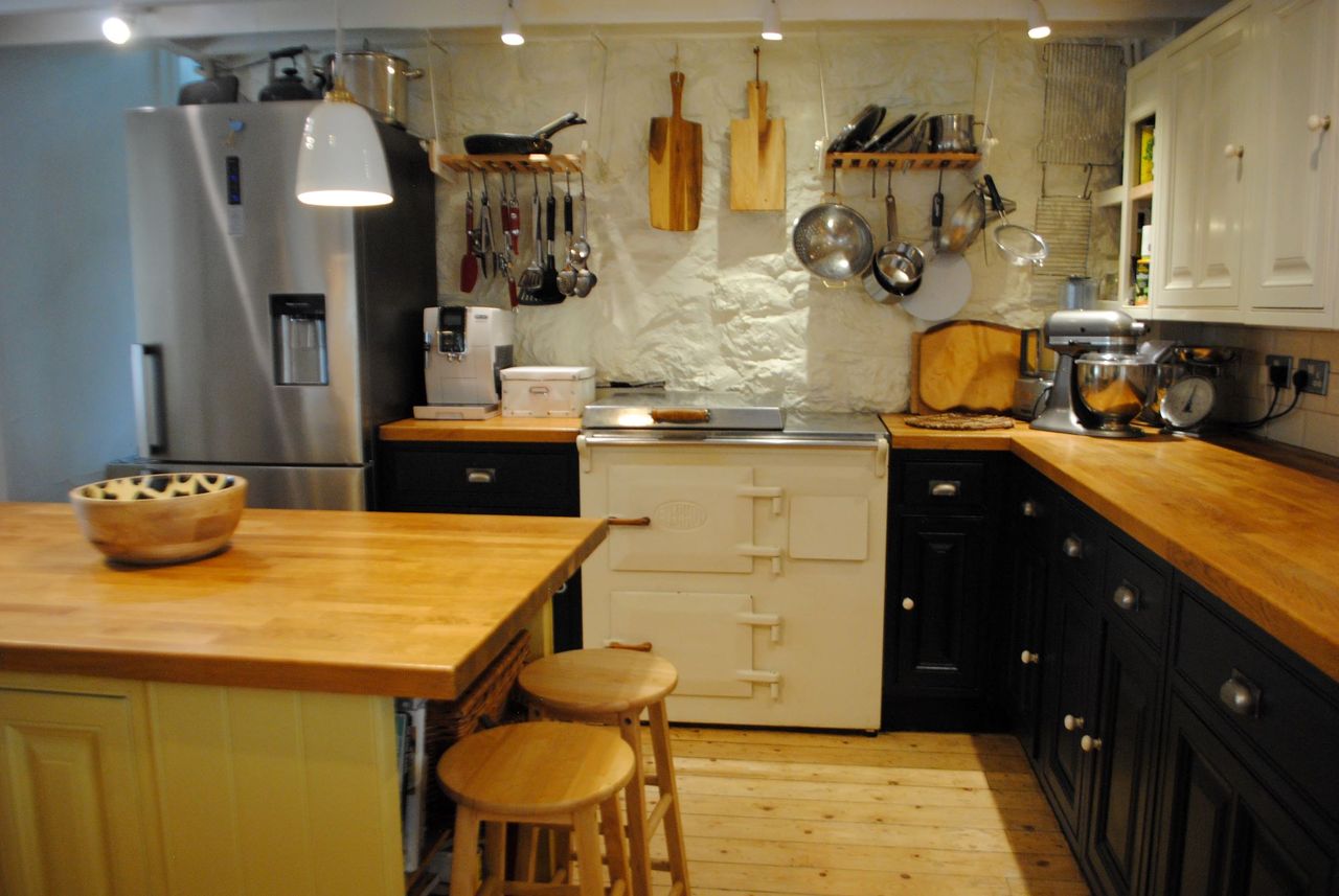 The kitchen has an island made from wood and the kitchen has wooden worktops throughout and white stone walls with a traditional oven is also included