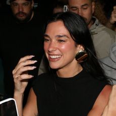 Dua Lipa wearing a black top, zebra bag, dark wash jeans