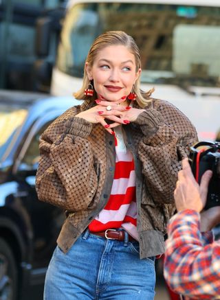 A photo of Gigi Hadid posing with her glossy red manicure and brownish red lipstick