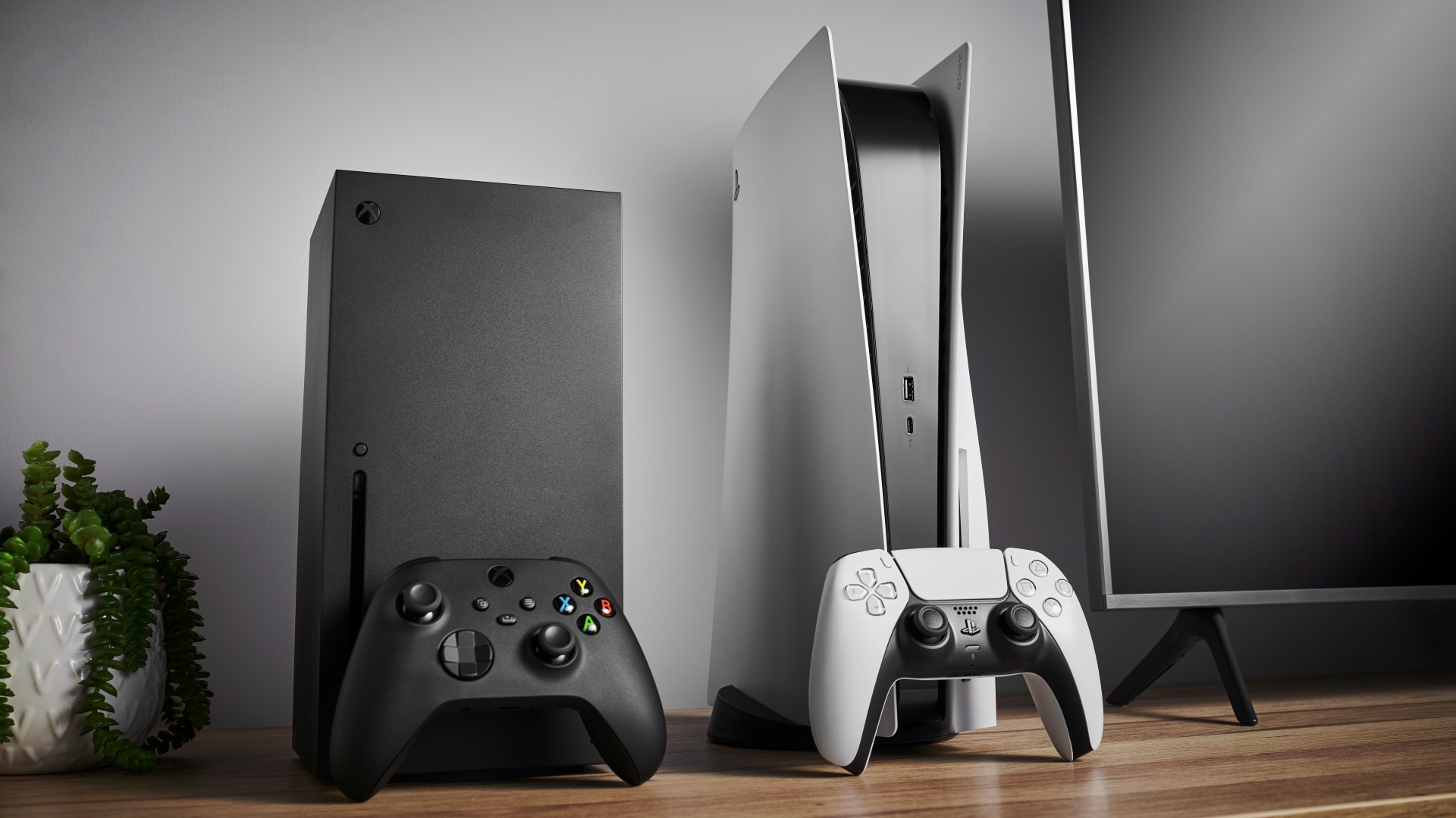 Living room with Microsoft Xbox Series X (L) and Sony PlayStation 5 home video game consoles alongside a television and soundbar