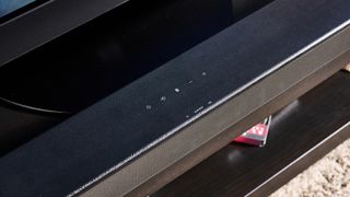 the sony ht-s100f or sony ht-sf150 in uk, a black soundbar with buttons on the top, a remote, photographed with a panasonic TV