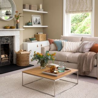 neutral living room with brown walls and white window and shelves, white mantel around a black fireplace, neutral sofa and industrial coffee table
