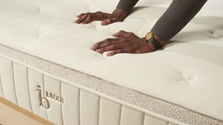 Man presses on sleep surface of the Birch Luxe natural mattress