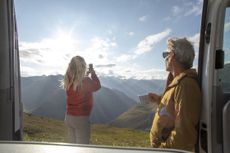 Woman takes photos of distant European Alps on cellphone
