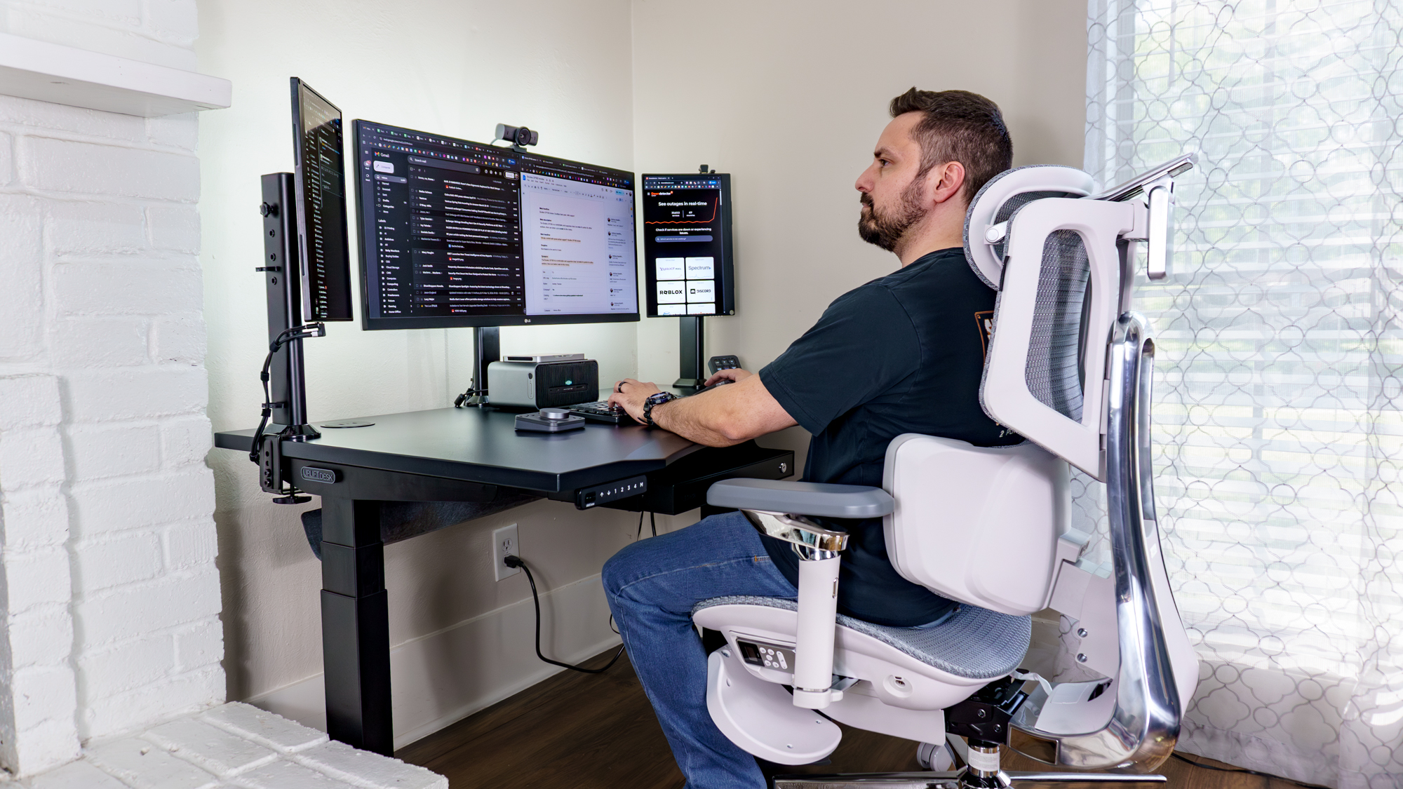 A person working at a triple monitor desk setup powered by the Mind 2S mini PC and Mind Graphics 2 eGPU dock