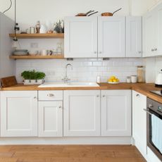 Kitchen with white walls, metro tiles and cabinetry with wooden countertops and floor